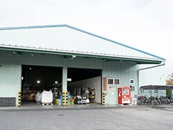 広いコンクリートの敷地に一棟の薄緑色のガルバリウム鋼板でできた大きな倉庫